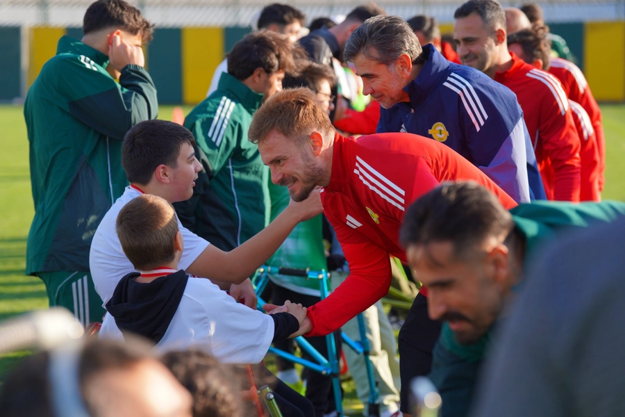 Sahada futbolcular ile çocuklar birbirleri ile konuşuyorlar