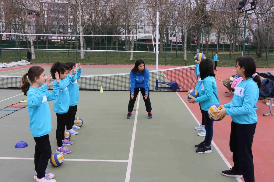Eğitmenle birlikte voleybol çalışan çocuklar